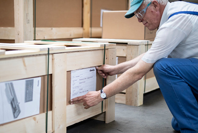 Versandmitarbeiter klebt Etikett an Versandkiste